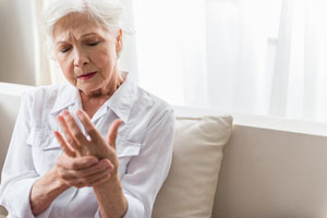 An older woman holding her hand due to arthritis pain.